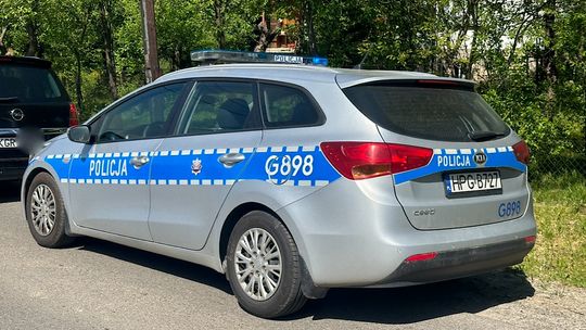 Samochód policyjny marki KIA, znajdujący się na poboczu, w słoneczny dzień