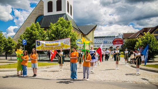 grupa kolorowo ubranych ludzi trzymających baner