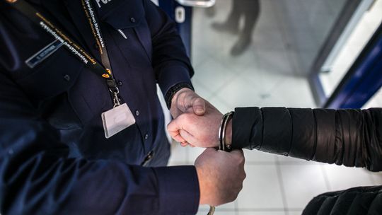 policjant zakłada kajdanki kobiecie