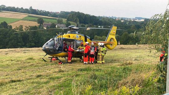 zdjęcie przedstawia śmigłowiec i ratowników i strażaków przy nim
