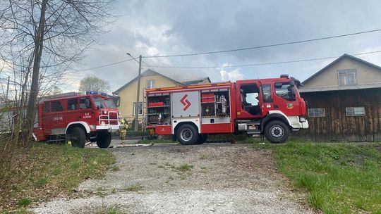 zdjęcie przedstawia wozy straży pożarnej przed domem z którego wydobywa się dym