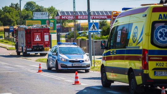 zdjęcie przedstawia policyjny radiowóz i karetkę z wozem straży pożarnej obok