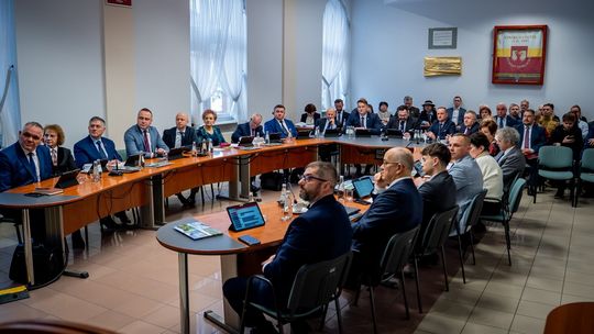 zdjęcie przedstawia grupę osób siedzących przy dużym stole