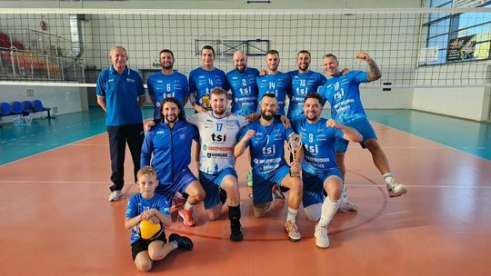 grupa sportowców w jednakowych strojach w hali sportowej, w tle siatka