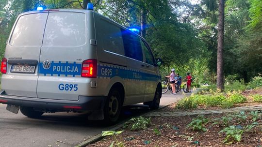 zdjęcie przedstawia radiowóz na tle drzew w parku