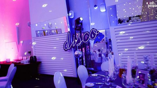 Spokój zamiast stresu. Kto odpowiada za udany event firmowy zdjęcie przedstawia stół zastawiony i napis disco nad nim