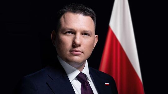 portret mężczyzny pod krawatem, obok flaga Polski