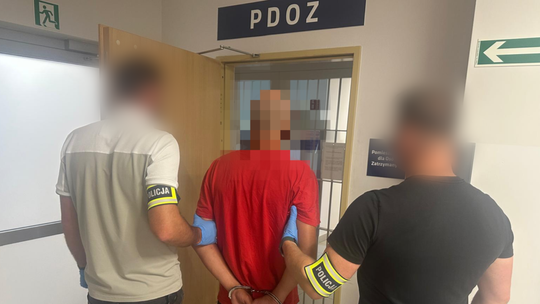 zdjęcie przedstawia policjantów prowadzących aresztowanego mężczyznę