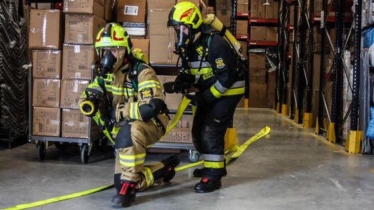 zdjęcie przedstawia dwóch strażaków w aparatach ochrony dróg oddechowych