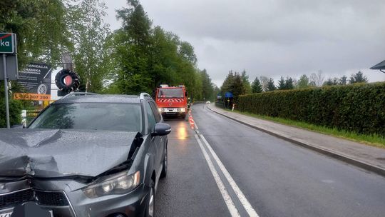 zdjęcie przedstawia uszkodzony pojazd na jezdni i za nią straż pozarną