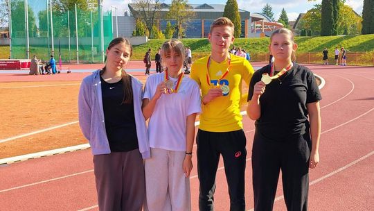3 dziewczyny i chłopak trzymający medale na bieżni stadionu
