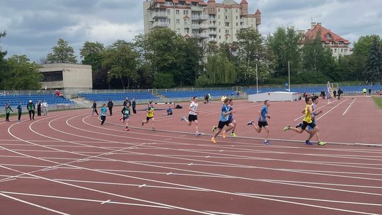 zdjęcie przedstawia biegnące po bieżni stadionu dzieci
