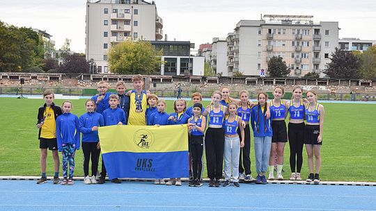 grupa dziewcząt i chłopców w strojach sportowych na stadionie lekkoatletycznym w Krakowie