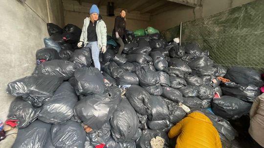 Kilka osób pakujących worki z odzieżą na tira