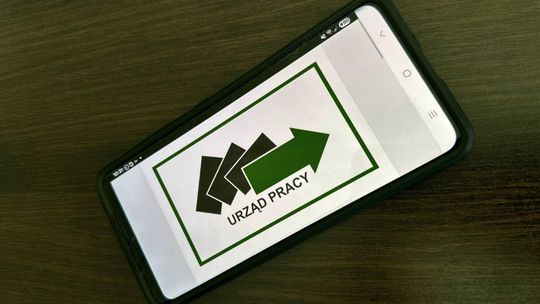 zdjęcie przedstawia telefon leżący na biurku, jest na nim logo powiatowy urząd pracy