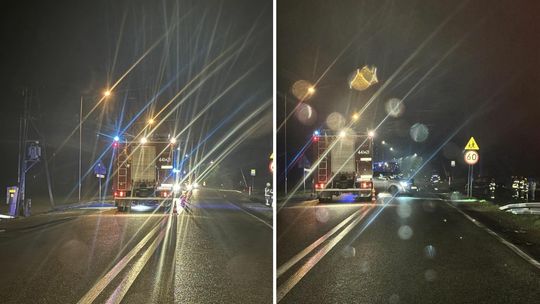 wozy strażackie stojące na drodze w nocy, mają włączone sygnały świetlne
