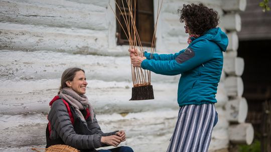 zdjęcie przedstawia kobietę która podaje pleciony koszyk innej kobiecie