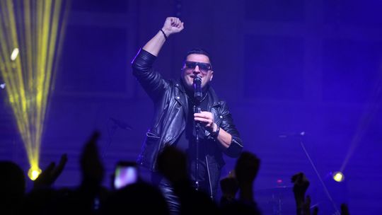 zdjęcie przedstawia mężczyznę w okularach przed mikrofonem