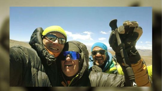 zdjęcie przedstawia mężczyzn z puchowych kurtkach na szczycie góry