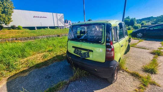 zdjęcie przedstawia zdezelowany samochód stojący na parkingu