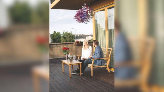 Taras nad garażem — jak go wykonać, żeby nie przeciekał? zdjęcie przedstawia kobietę i mężczyznę siedzących na tarasie popijających kawę