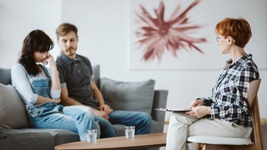 zdjęcie przedstawia dwie osoby na kozetce, obok kobieta na krześla
