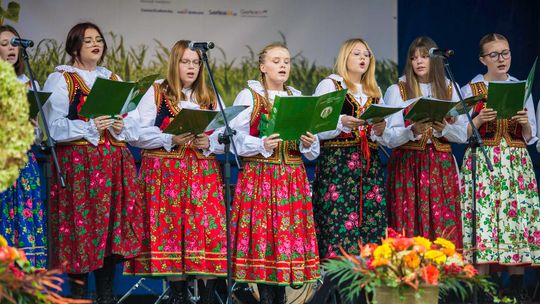 dziewczyny w ludowych strojach śpiewają na scenie