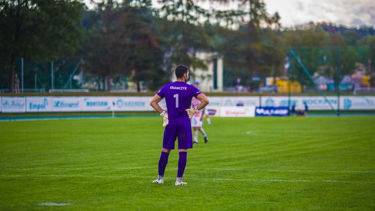zawodnik we filetowym kostiumie bramkarza podczas meczu piłkarskiego na boisku