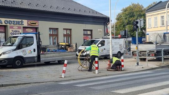 pracownicy w żółtych kamizelkach na chodniku ulicy w mieście, obok nich stoją samochody na Zawodziu w Gorlicach