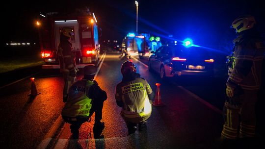 zdjęcie przedstawia policjanta i strażaka kucającego na jezdni