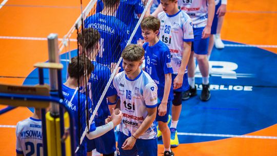 grupa młodych siatkarzy pod siatką w hali sporotowej, podają sobie ręce