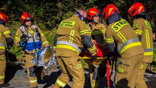 zdjęcie przedstawia strażaków niosących rannego na noszach