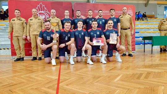 zdjęcie przedstawia grupę mężczyzn w strojach sportowych, obok mężczyźni w mundurach strażaków