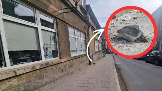 W centrum miasta spory kawałek gzymsu spadł z budynku na chodnik zdjęcie przedstawia budynek przy miejskiej ulicy z chodnikiem, na nim kawałek gruzu