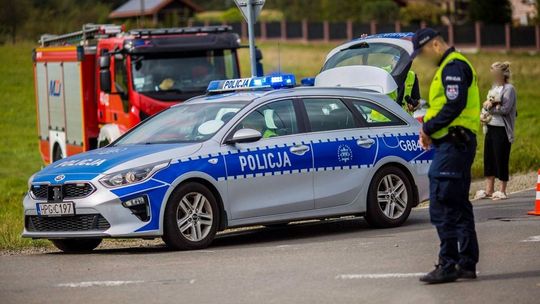 radiowóz na jezdni, obok policjant