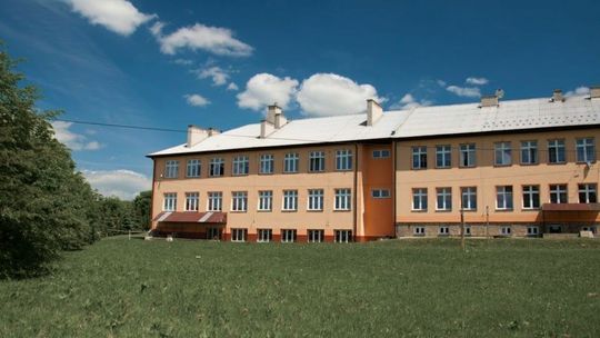 budynek szkoły z łąką przed nią