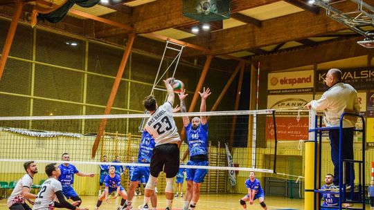 zdjęcie przedstawia zawodników skaczących przy siatce w hali sportowej