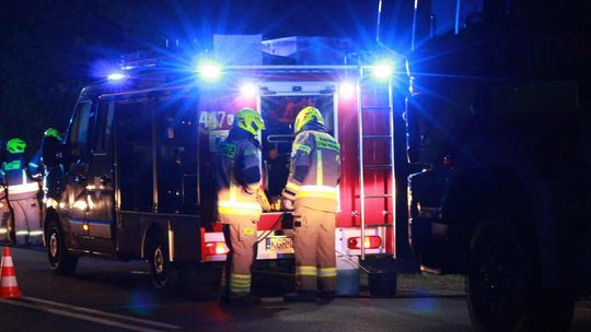 zdjęcie przedstawia strażaków przy samochodzie strażackim w nocy