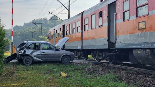 wrak samochodu po zderzeniu z pociągiem, który stoi na torach za pojazdem