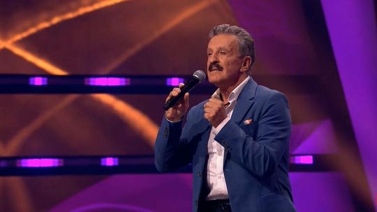 zdjęcie przedstawia mężczyznę z mikrofonem na scenie