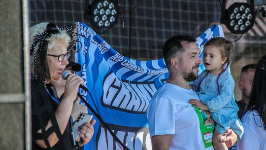zdjęcie przedstawia dziewczynkę (Nikola Woźniak) na rękach mężczyzny podczas pikniku w Sękowej