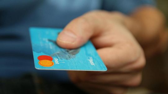 zdjęcie przedstawia kartę bankową trzymaną przez męską dłoń