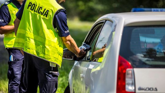 policjant z alkomatem przy samochodzie przeprowadzają kontrolę trzeźwości