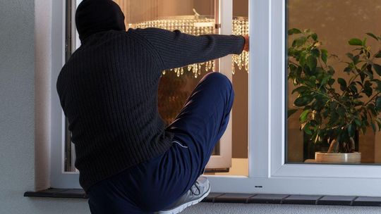 zdjęcie przedstawia mężczyznę wchodzącego przez okno do mieszkania