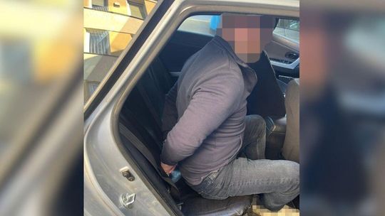 zdjęcie przedstawia zakutą w kajdanki osobę w samochodzie