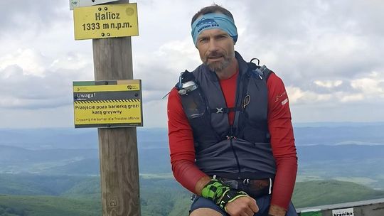 zdjęcie przedstawia mężczyznę na szczycie wzniesienia, obok drogowskazy