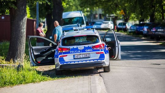 radiowóz stojący tyłem, otwarte drzwi przednie z których wysiadają policjanci