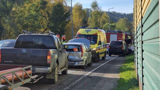 uszkodzone pojazdy stojące na jezdni, obok policjanci i strażacy