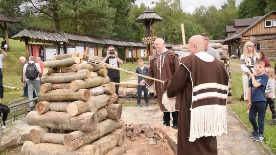 zdjęcie przedstawia dwóch mężczyzn trzymających pochodnię nad ogniskiem