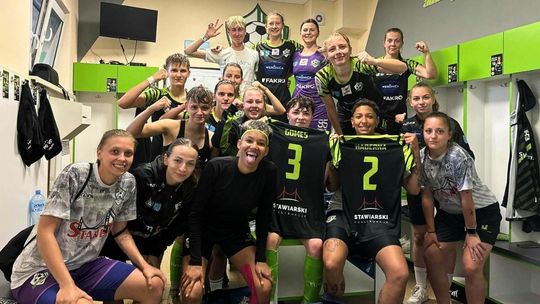 grupa dziewcząt w strojach sportowych w szatni ciesząca się ze zwycięstwa w 1. lidze piłki nożnej kobiet